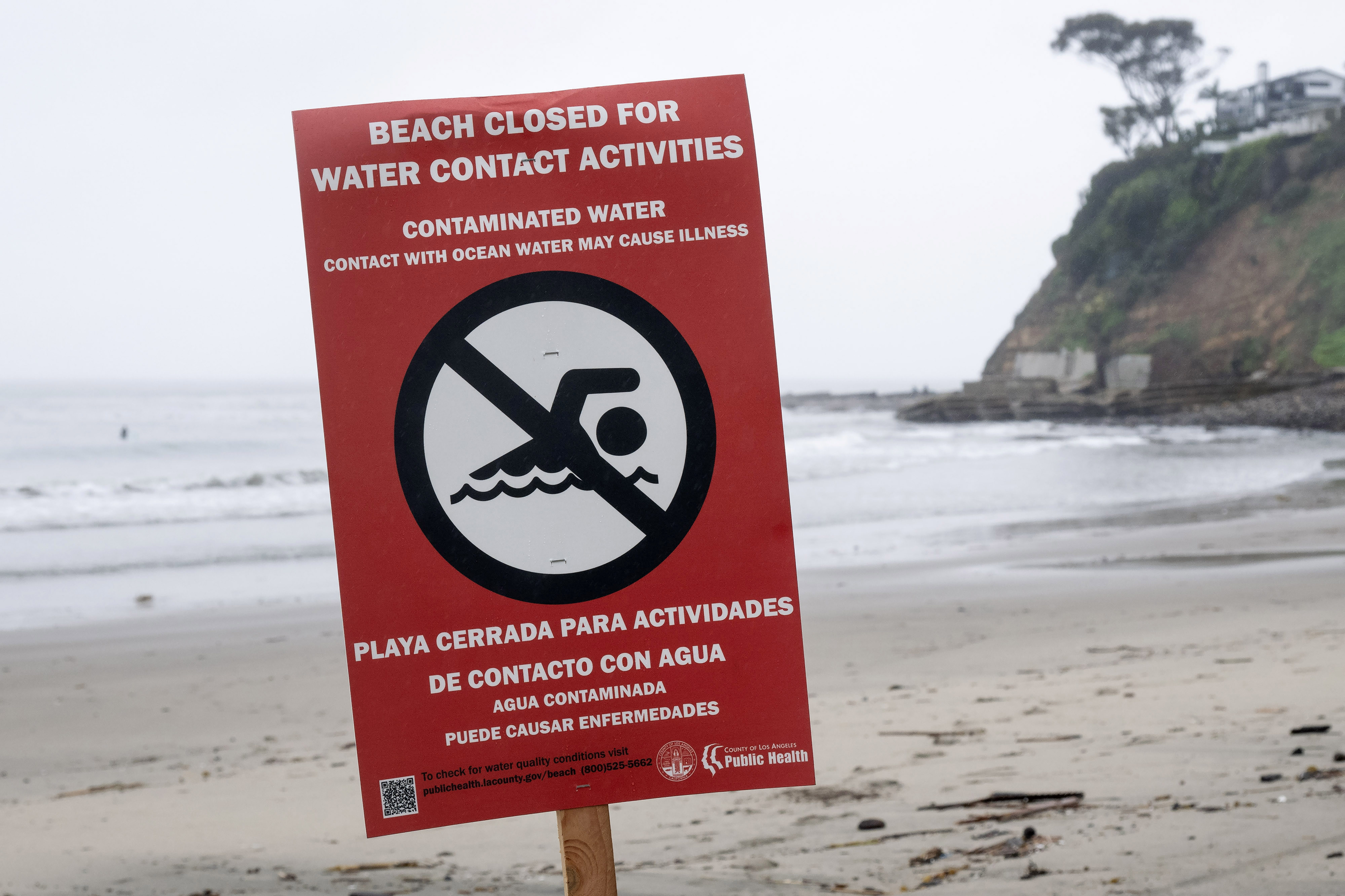 Beach closure signs are posted on the south side of...
