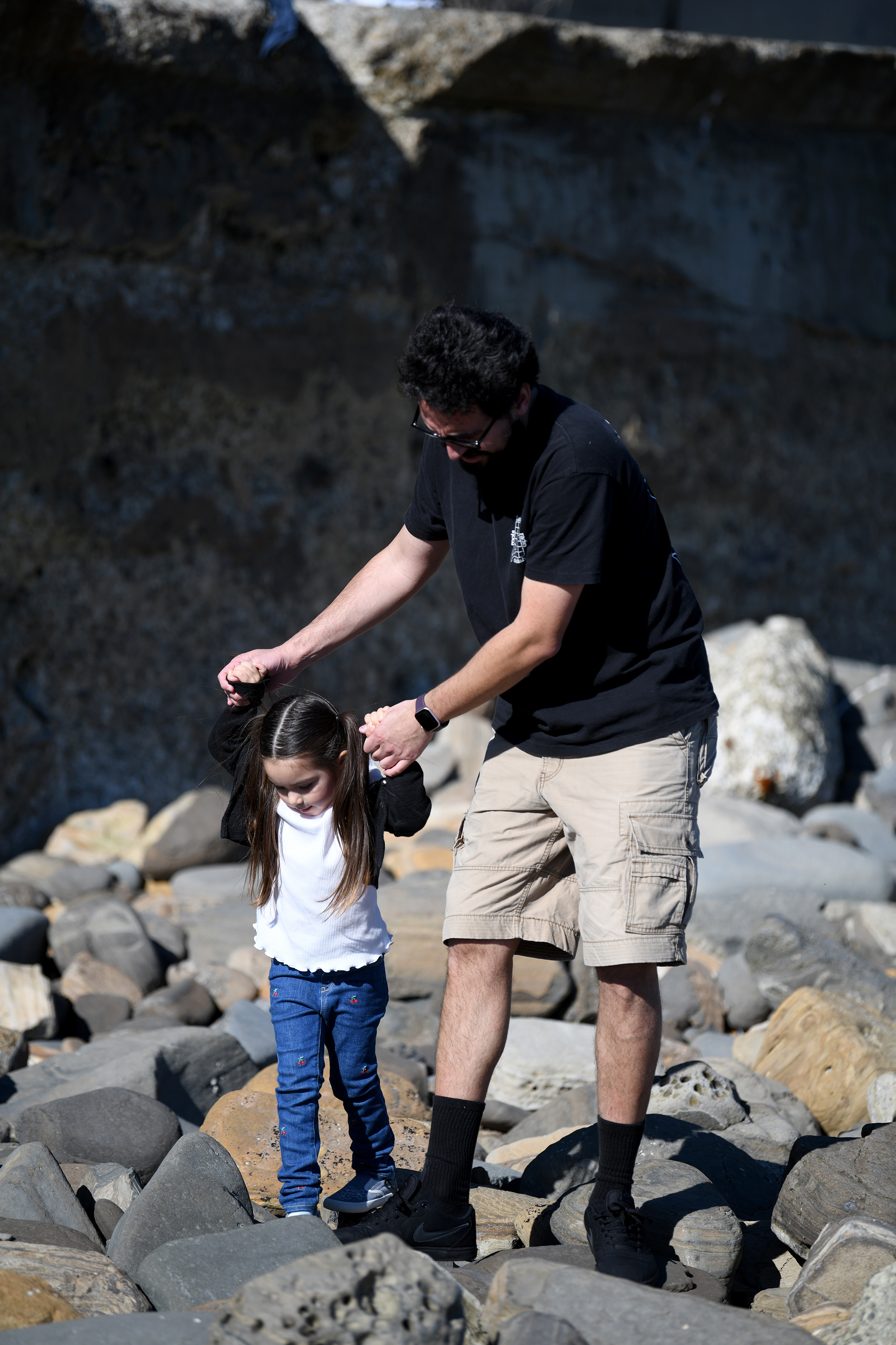 Fernando Martinez helps his daughter Julianna, 3, climb to the...