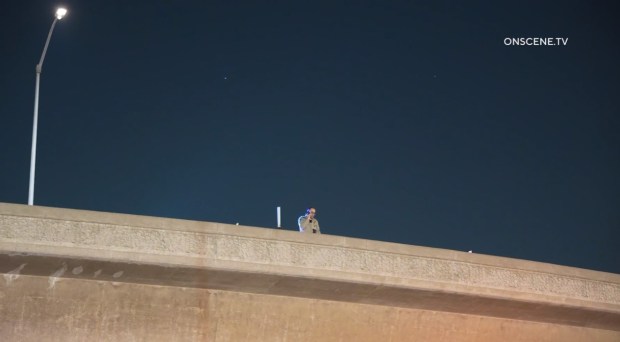A California Highway Patrol officer looks down on a crash scene after a car being pursued flew off the 105 Freeway near Los Angeles International Airport early on Jan. 25, 2026. (Photo by OnScene.TV)