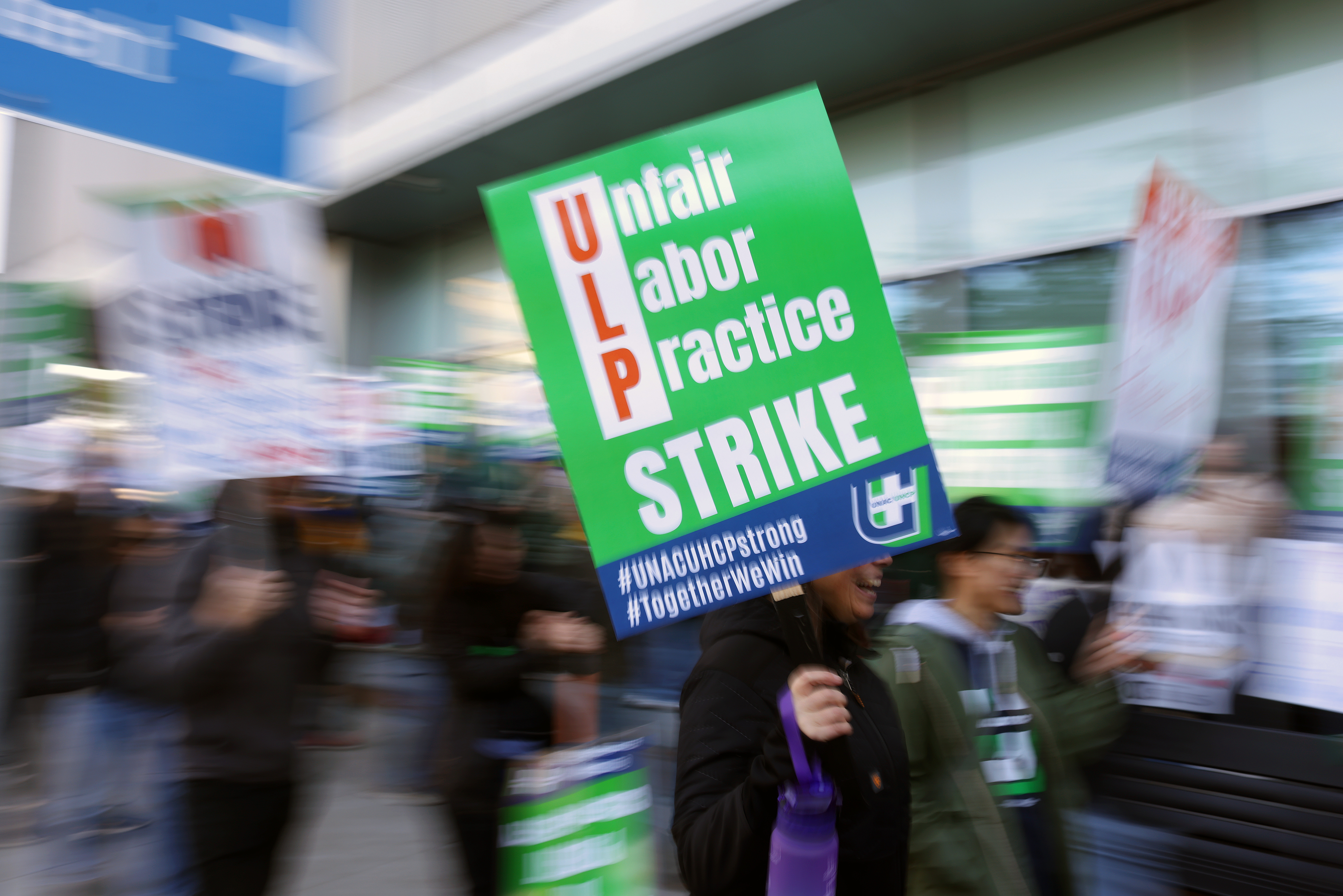 Medical workers and their supporters walk a picket line outside...