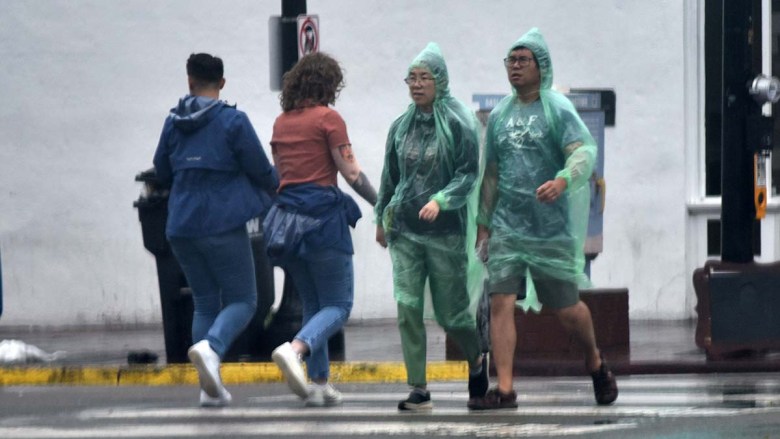 People walked downtown amid rain and wind in downtown San Diego. Photo by Chris Stone