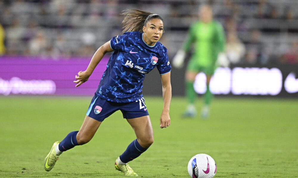 A soccer player in a blue uniform controls the ball on the field