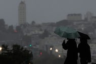 People carried umbrellas while walking on a path at Alamo Square Park, in San Francisco,...