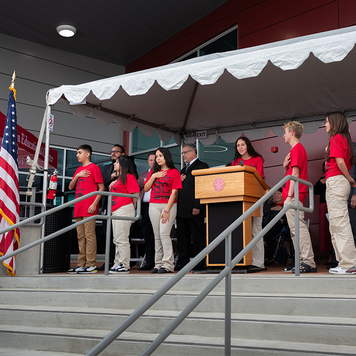 students saluting the American flag during grand opening