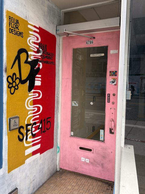 A pink door with a glass panel at 4786 catches the Excelsior buzz, set next to a yellow and red mural with "BEIJA FLOR DESIGNS" and black graffiti. Stickers and a small keypad adorn the door.