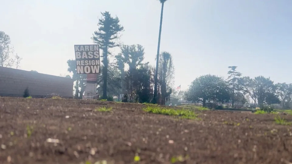 A sign calling for Los Angeles Mayor Karen Bass to resign is displayed on a vacant lot.