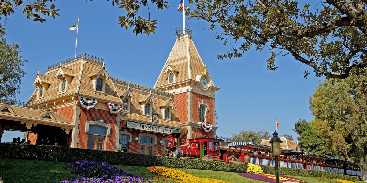 Main Street, U.S.A, station with the Disneyland Railroad train arriving at the station above the Mickey Mouse floral array that greets guests in the entrance to Disneyland Park as facial recognition begins.