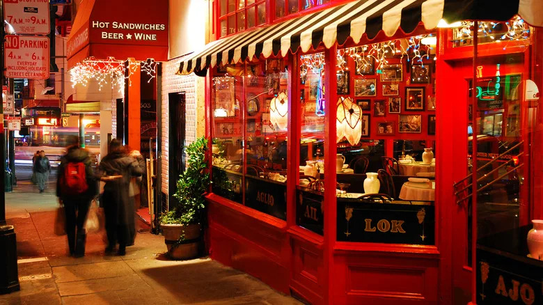 People walking in front of a red restaurant with string lights