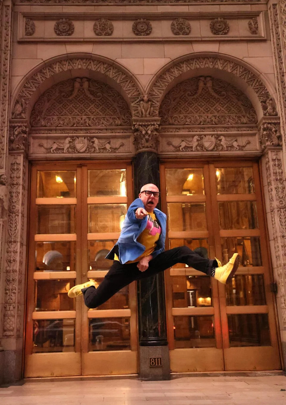 A man leaps in the air in front of a vintage building.
