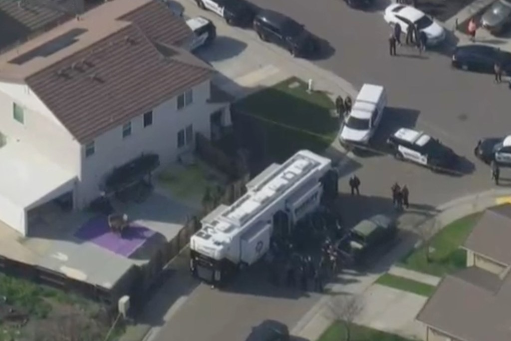 Aerial view of law enforcement vehicles and officers on a residential street.