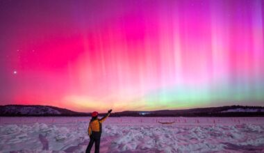 Photo of a person stood in front of pink auroras in China