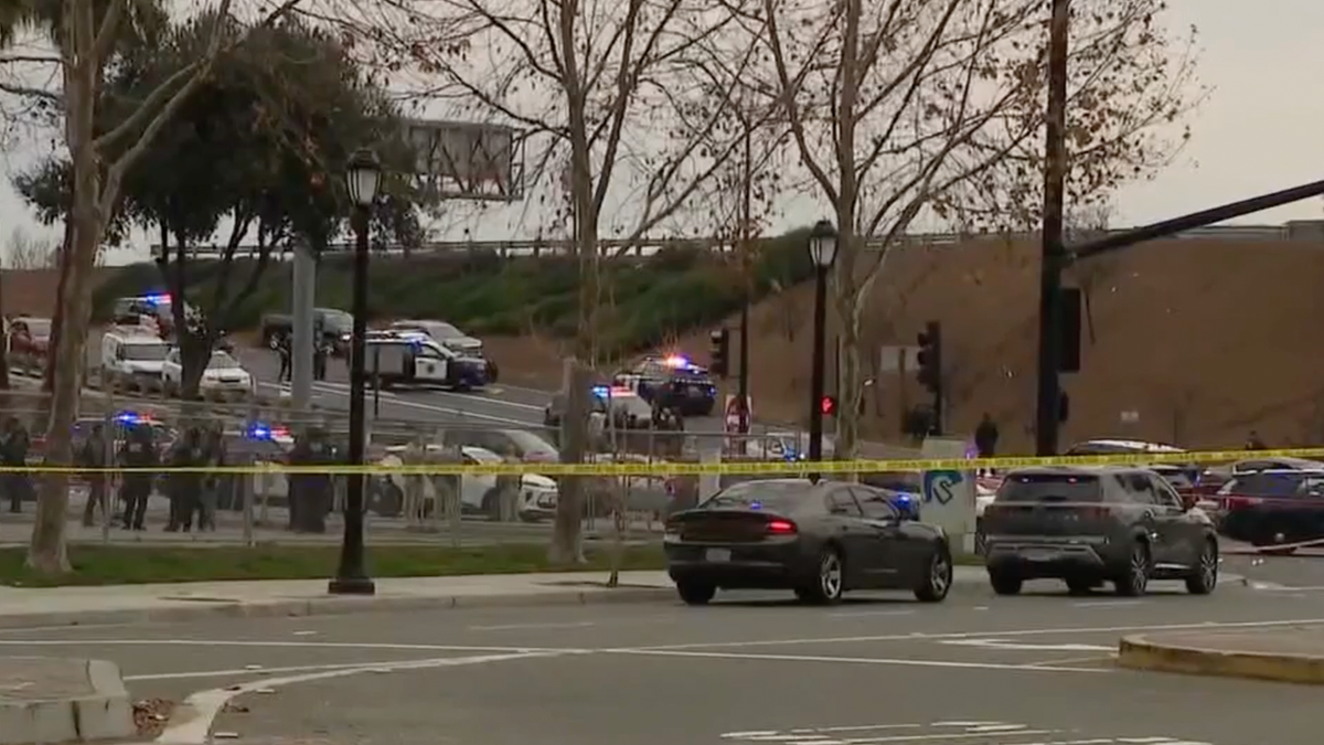 Police vehicles and officers block an intersection behind yellow tape in San Jose