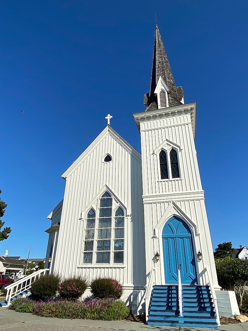 A white church with baby-blue door and tall steeple.