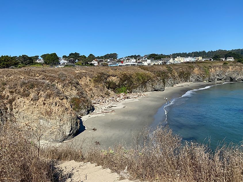 A wooden staircase leads down through the thicket to a sizeable tidal beach at the foot of sheer cliffs.