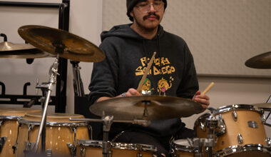 male student wearing a beanie sitting at a drum set