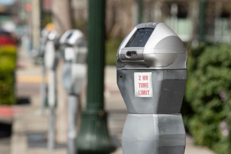 A street parking meter with a sticker that reads "two hour limit"