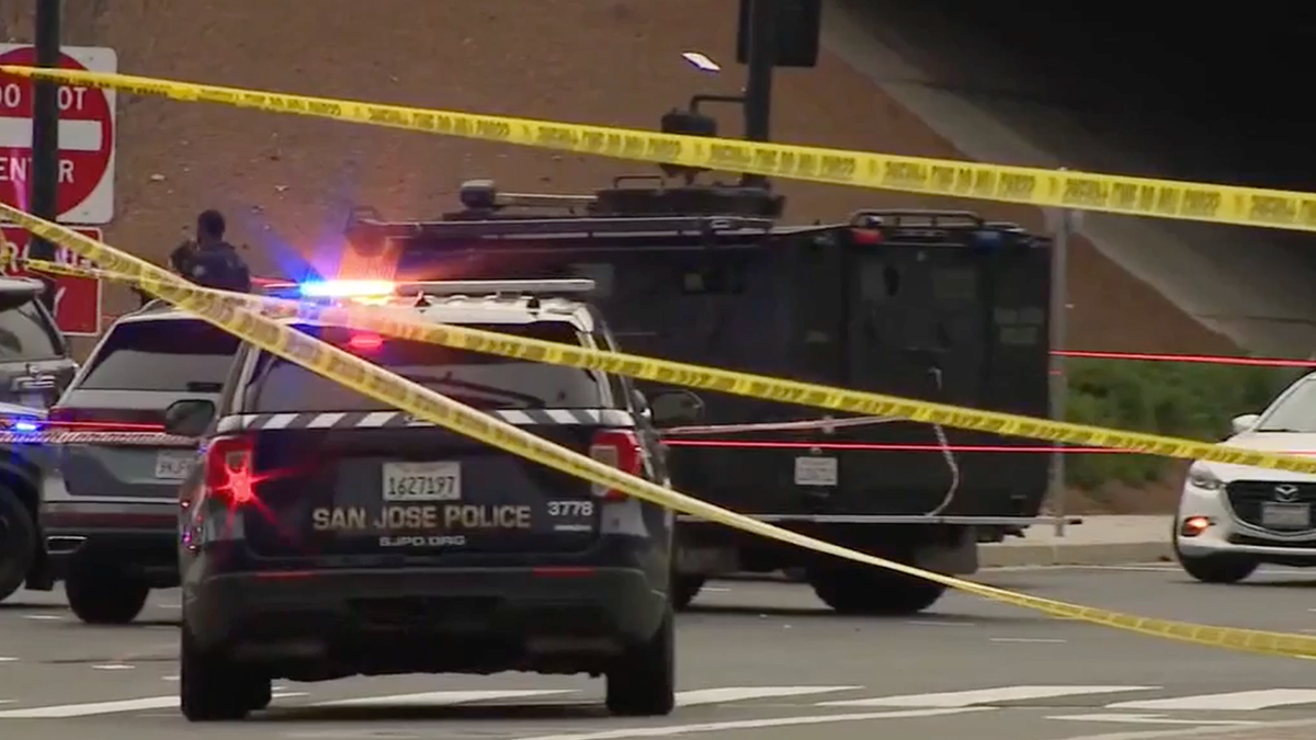 San Jose police vehicles and an armored vehicle block an intersection behind police tape