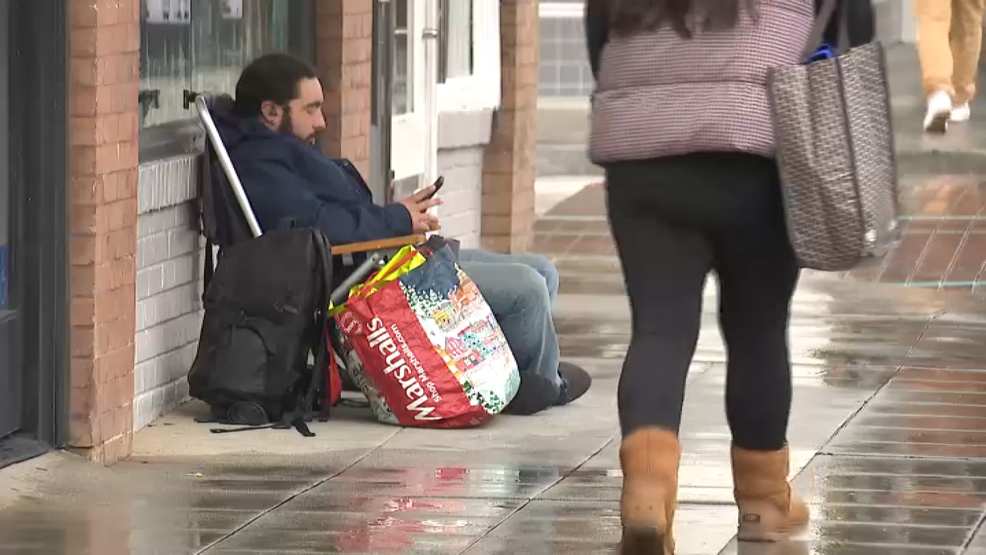 A man sits along Colorado Boulevard to save a spot to view the Rose Parade.