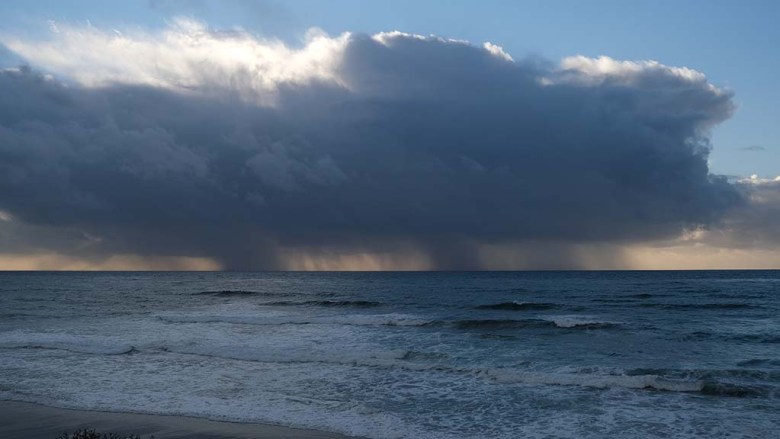 Rain clouds off the coast at Windansea dump water over the ocean.
