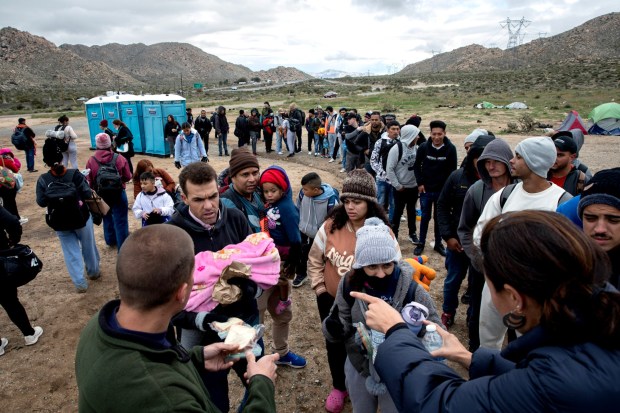 Volunteers hand out water and peanut butter and jelly sandwiches to more than 60 migrants who arrived to a camp just off of Interstate 8 waiting to be processed by U.S. Border Patrol on Friday, March 15, 2024 in outside of Jacumba Hot Springs, California. People came from Pakistan, Brazil, Dominican Republic, Bolivia, Honduras, Egypt, Somalia and other countries. (Ana Ramirez / UT file)