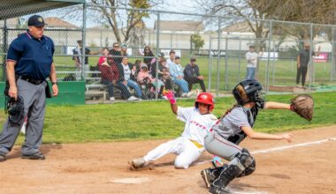 Young girl slides to homebase as umpire watches from side and catcher squats in anticipation of a throw.