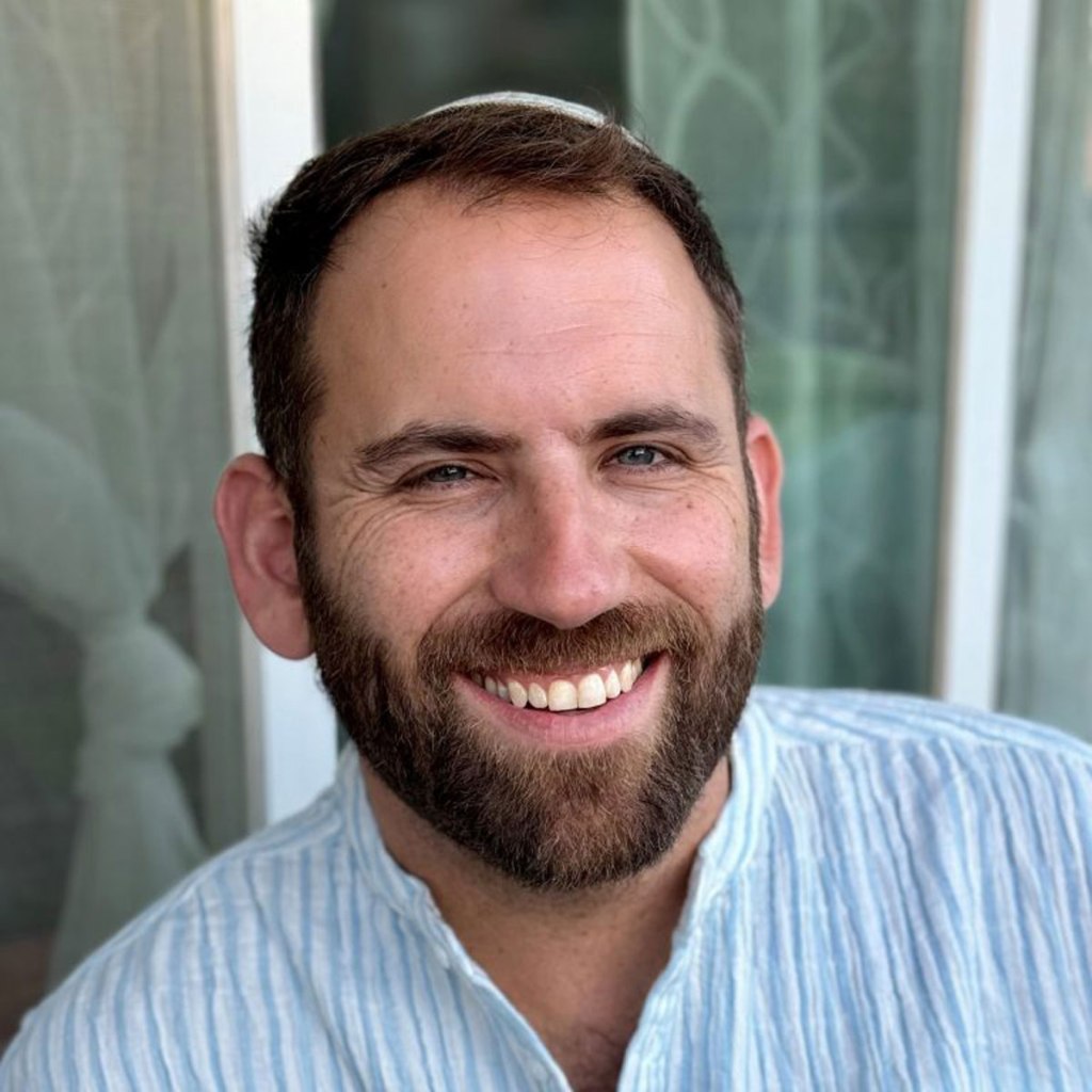 Rabbi Hanan Leberman, wearing a kippah and striped shirt, smiles at the camera.
