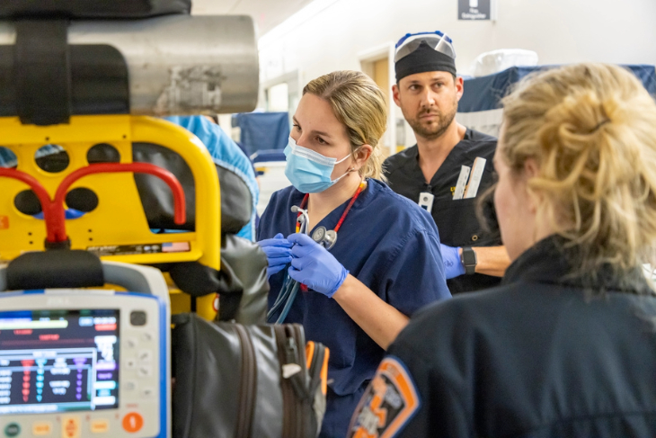 A medical team collaborates in a busy emergency department as they assess and care for a patient brought in by first responders.