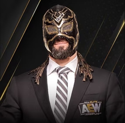 A man poses in a suit and tie with a wrestling mask on.