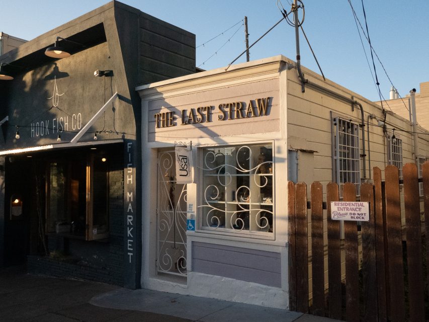 A small building with a sign reading "The Last Straw" next to Hook Fish Co.; a "Residential Entrance" sign is posted on a wooden fence in the foreground.