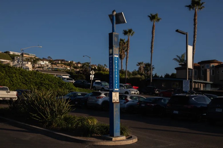 A blue pole labeled "emergency" is seen in the middle of a parking lot.