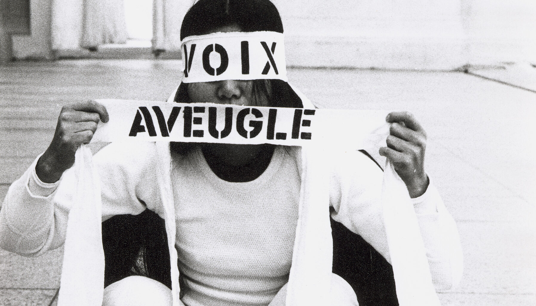 black and white image of woman squatting in white with eyes and mouth covered by 'voix' and 'aveugle'