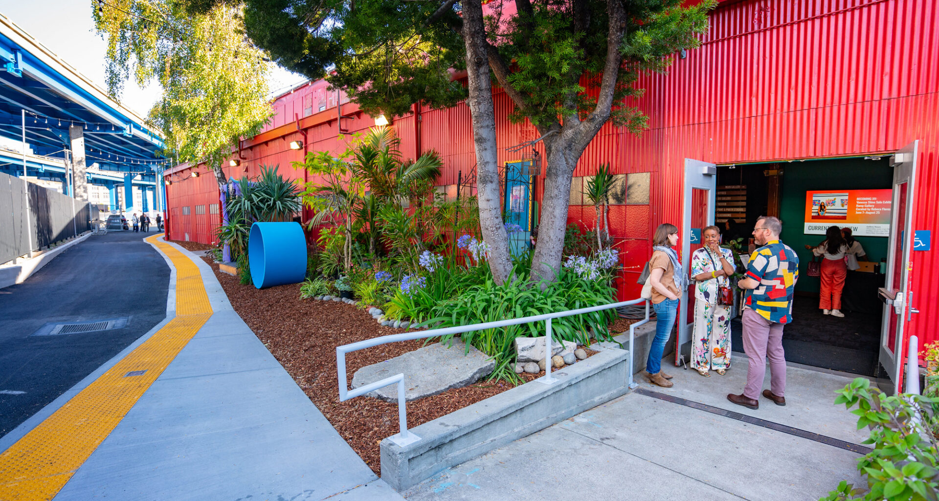 doorway with people chatting in red-painted building beside freeway