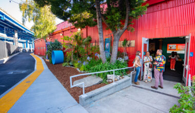 doorway with people chatting in red-painted building beside freeway