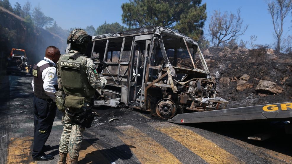 A soldier stands guard by a charred vehicle that was set on fire in Cointzio, Mexico, Sunday, Feb. 22, 2026, amid reports the Mexican Army killed Jalisco New Generation Cartel leader Nemesio Oseguera, known as "El Mencho." (AP Photo/Armando Solis)