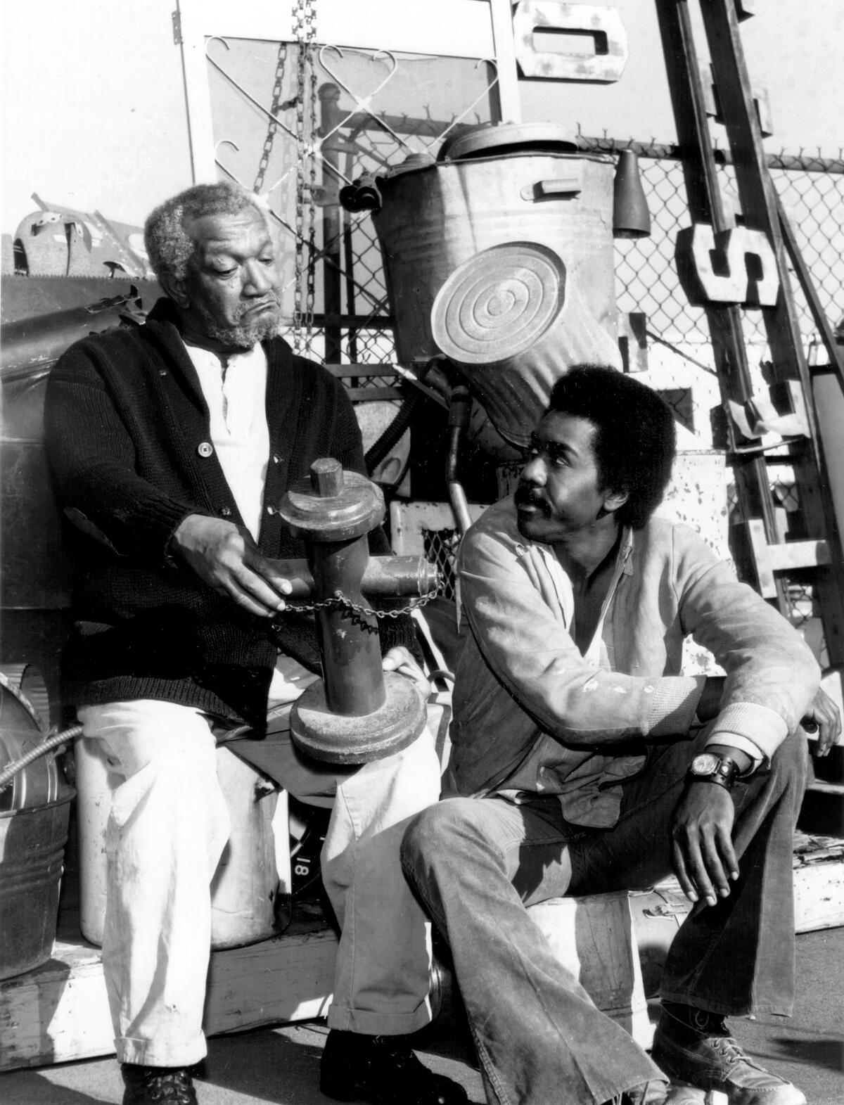  Redd Foxx and Demond Wilson sit together on the set of "Sanford and Son."