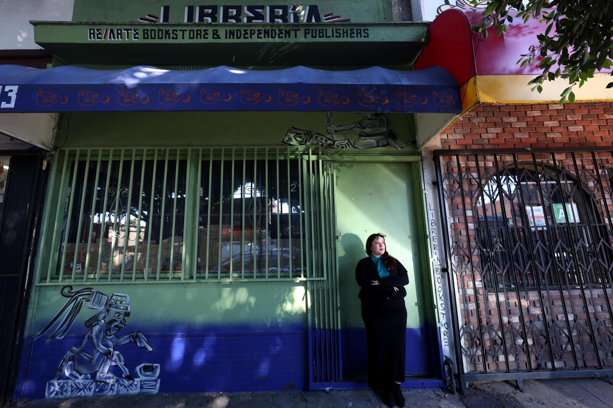 A woman stands in front of a closed storefront.