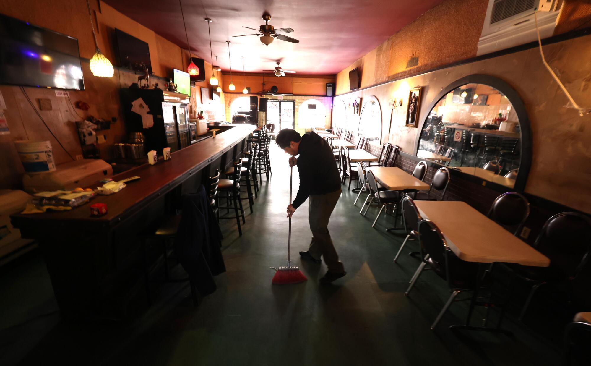 A man sweeps the floor in a restaurant.