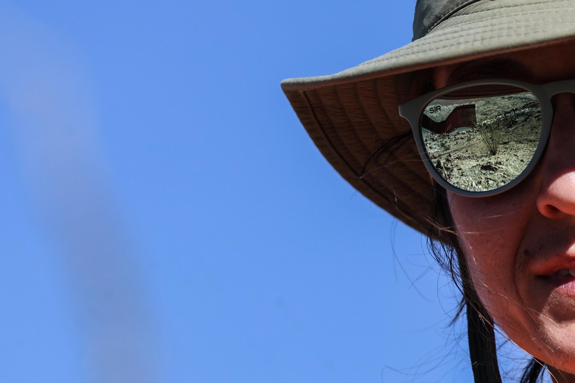 The border wall is reflected in wildlife biologist Christina Aiello's sunglasses.