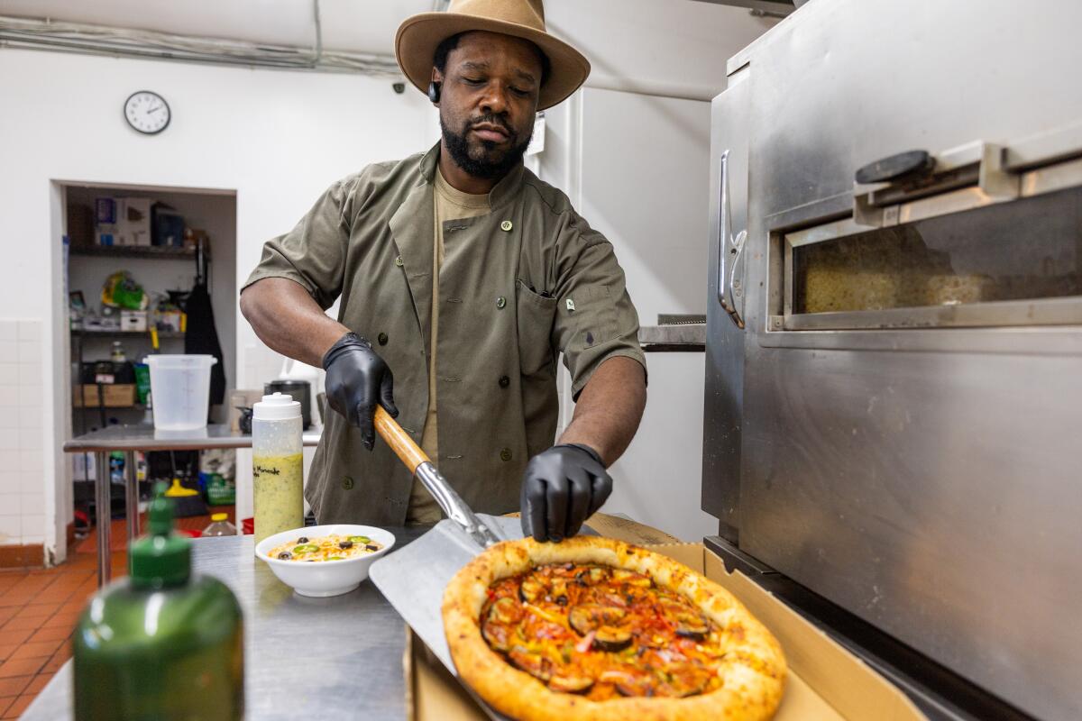 Chef Amin Muhammad places a vegan zucchini pizza into a pizza box at the Crenshaw Food Hub. 