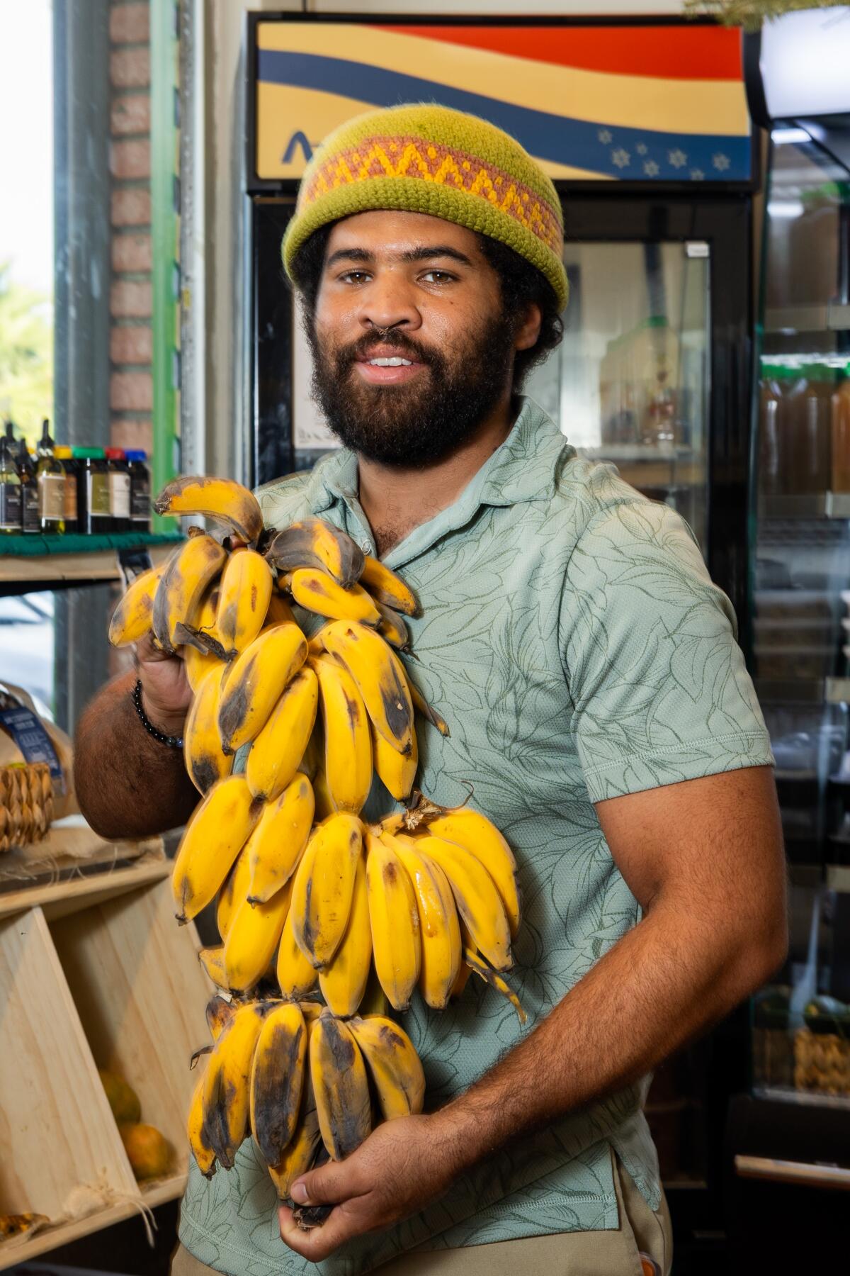 Imani Diggs of Imani Gardens holds a large bundle of bananas at the Crenshaw Food Hub. 
