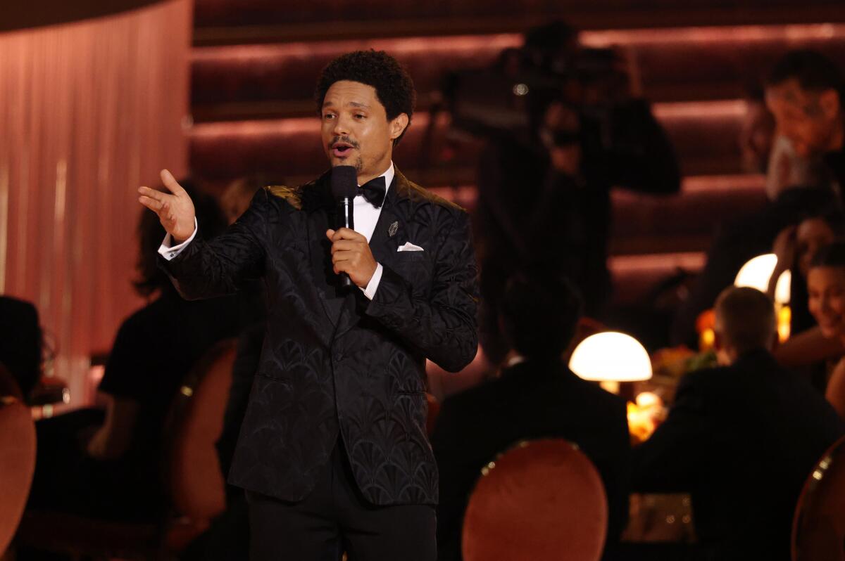 Trevor Noah talks into a microphone at the Grammys. 