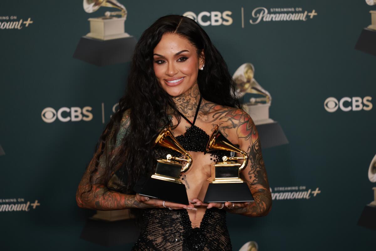 Kehlani holds a Grammy in each hand.