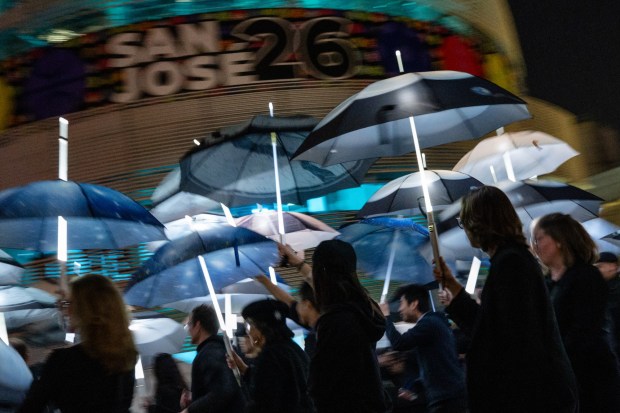 Participants march with umbrellas printed with aerial photographs at City Hall in San Jose, Calif., on Saturday, Jan. 31, 2026. (Thien-An Truong for Bay Area News Group)
