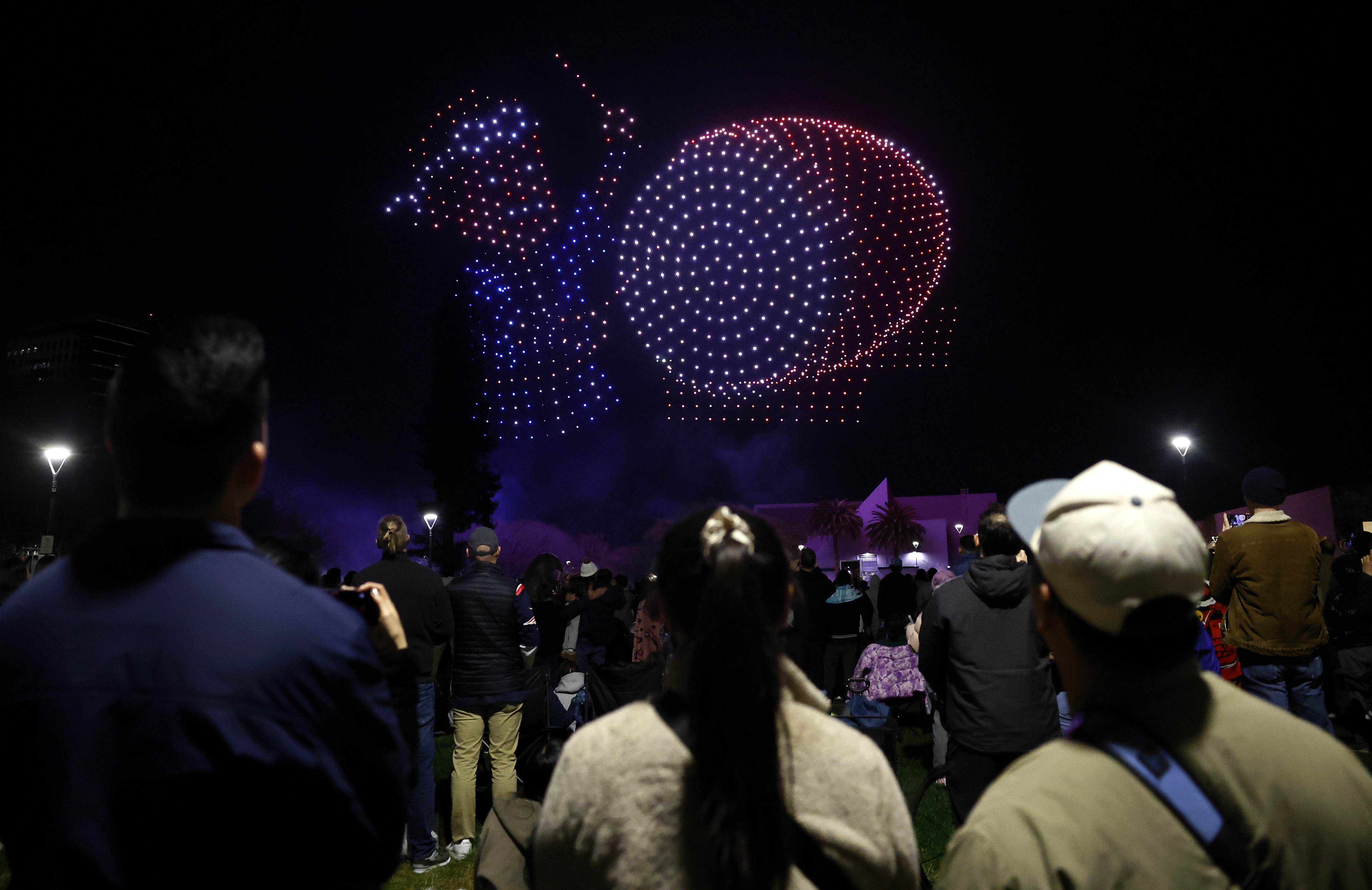 People watch a drone show which depicts a San Jose...