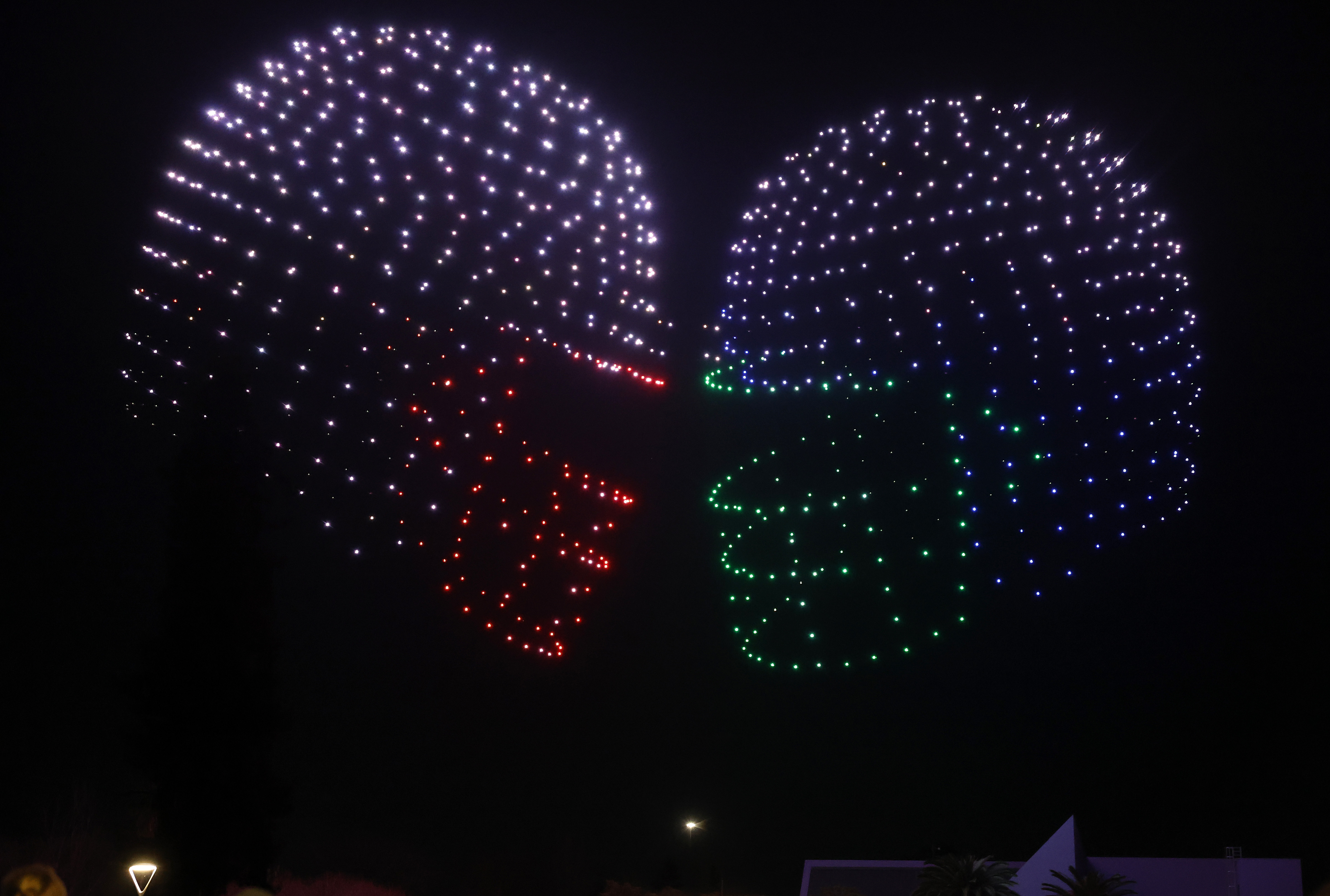 People watch a drone show depicting football helmets in Discovery...