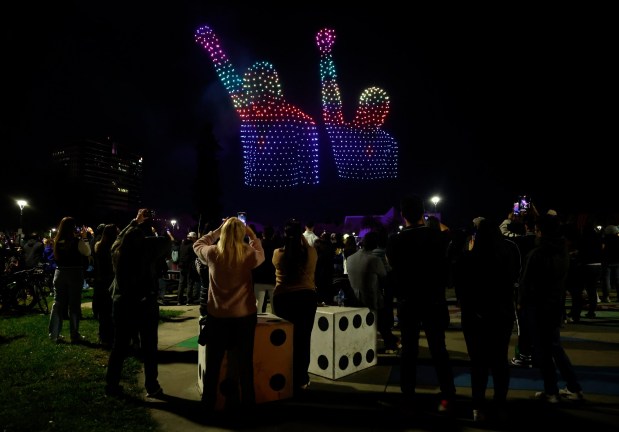 People watch a drone show which depicts San Jose State University alumni Tommie Smith and John Carlos in Discovery Meadow on Super Bowl Opening Night in downtown San Jose, Calif., on Monday, Feb. 2, 2026. They performed a Black power salute during the medal ceremony for the 200 meter final in Mexico City in 1968. (Nhat V. Meyer/Bay Area News Group)