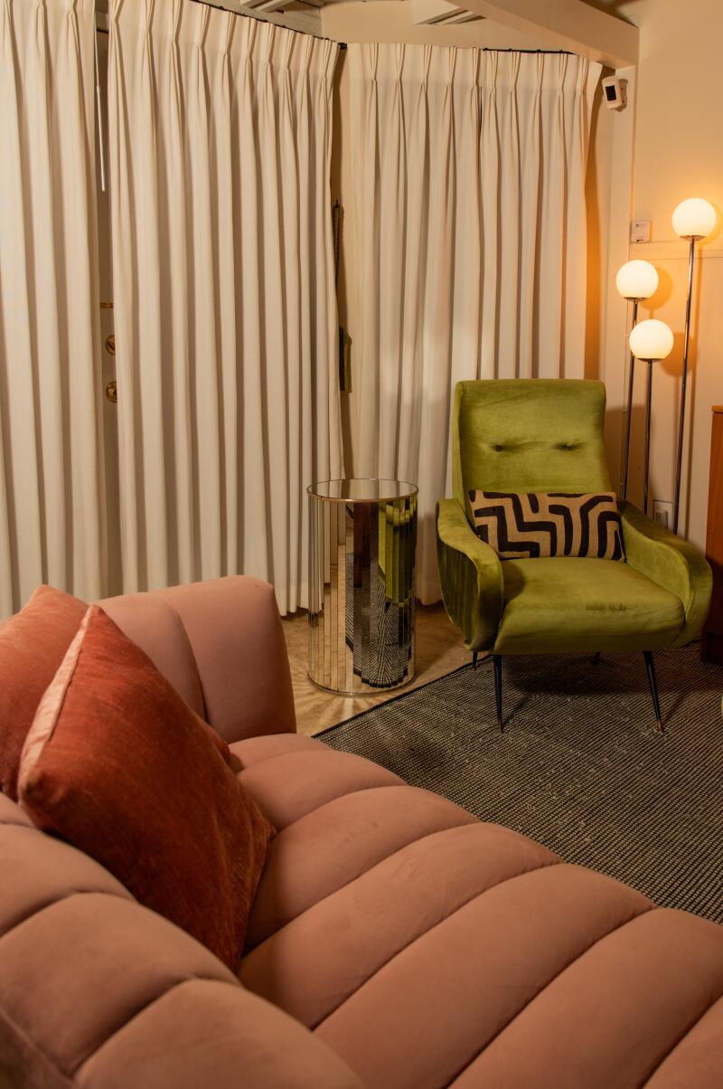 The living room of Adams' home consists of bright velvet pieces, a mirrored side table and white drapes.