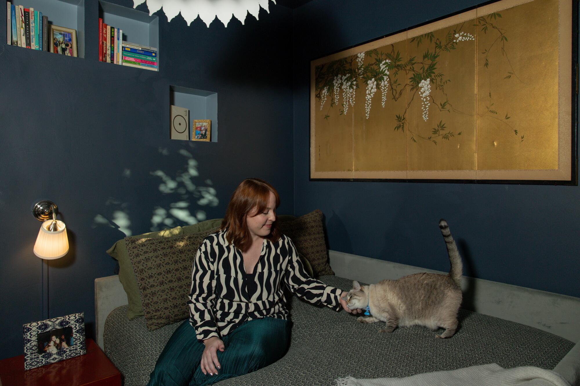 Tori Adams and her cat Cami sit in her bedroom.