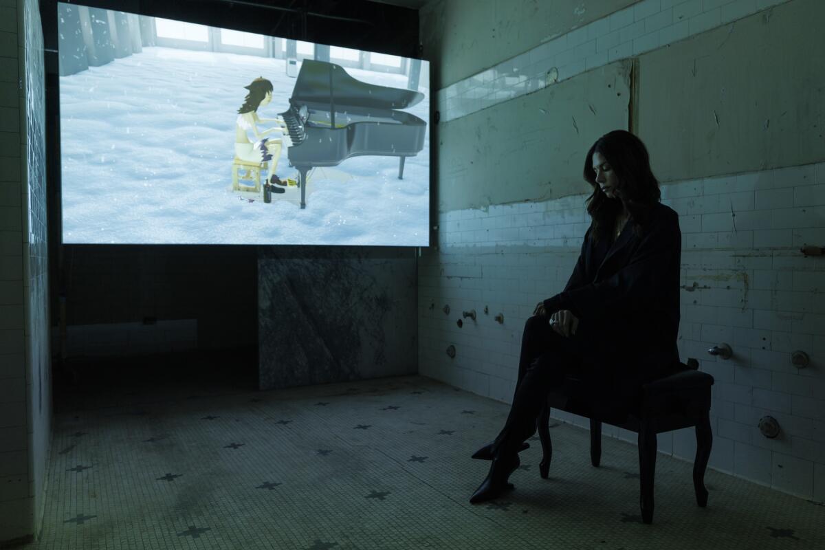 A woman sits in front of a movie screen.