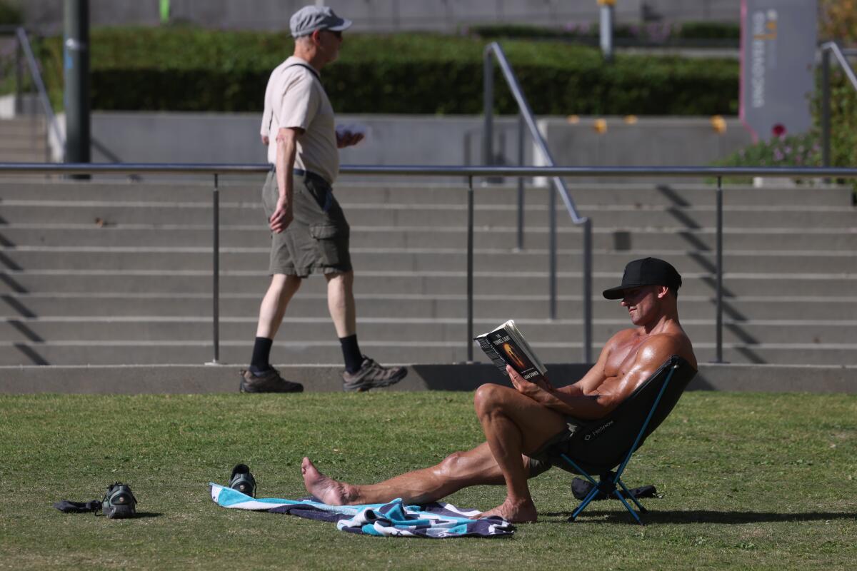 A man reads a book in a lawn chair at Gloria Molina Grand Park.